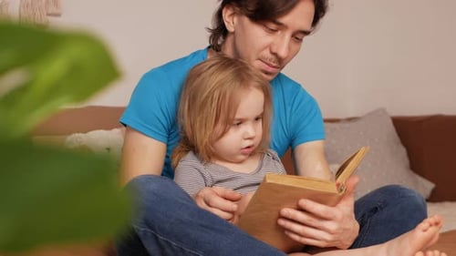 Man Reading Book With Little Girl Indoors