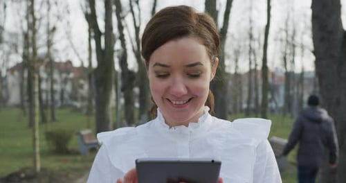 Woman Uses Tablet Device in Urban Park