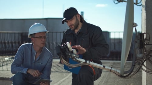 Two Men Inspect Satellite Dish on Rooftop