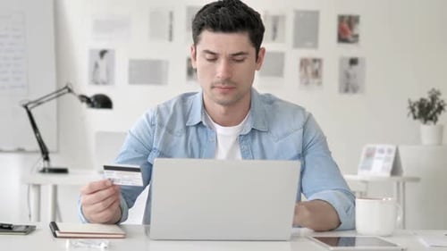 Man Using Credit Card and Laptop Looks Distressed