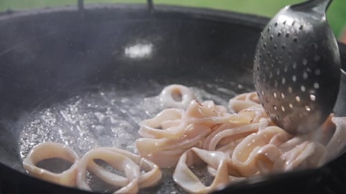 Squid Rings Cooking in Pan with Spoon