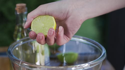 Hand Squeezing Fresh Lime into Glass Bowl