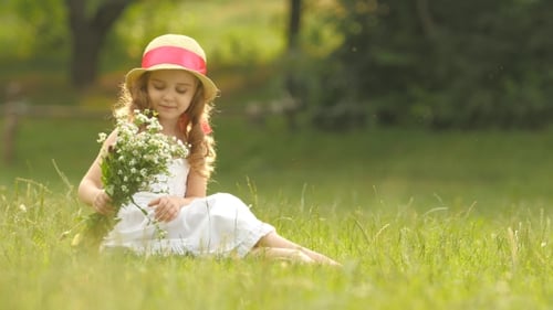 Girl Sits in Field Smelling Wildflowers