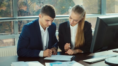 Businessman Signs Documents at the Office. The Secretary Helps Him