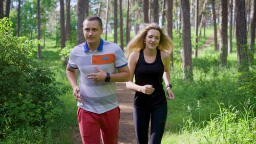 Friends Who Lead an Active Lifestyle, Run Along a Country Road in the Park, a Man and a Woman in