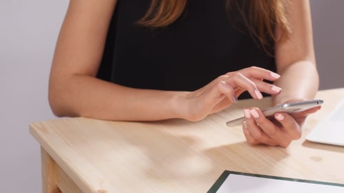 Jeune femme travaille dans le bureau derrière un ordinateur avec un smartphone