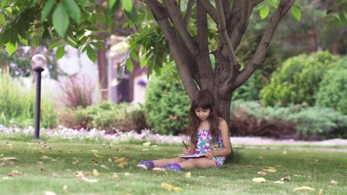 Kid Paint Sitting on the Grass Under a Tree. Little Girl Draw with Crayons in the Back Yard