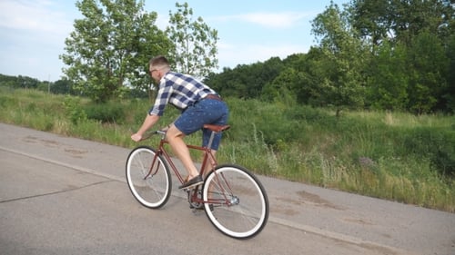 Junger gutaussehender Mann fährt auf Oldtimer-Fahrrad auf der Landstraße. Sportlicher Typ beim Radfahren auf der Rennstrecke