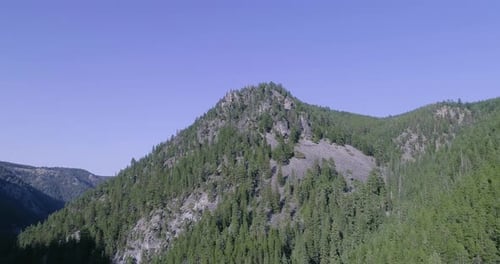 Aerial dolly forward shot towards and above high mountain in canyon.