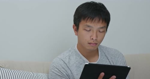 Young Adult Using Tablet Device at Home