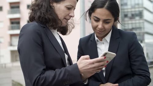Women Discussing Information on Cellphone Outdoors