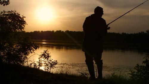 Fischer fängt Fische auf einer Angelrute Sonnenuntergang umhüllt wunderschön seine Silhouette