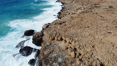 Sea Washes the Rocky Shore Above Aerial Shot Flying Over Coastline Cliffside with Blue Pure Water