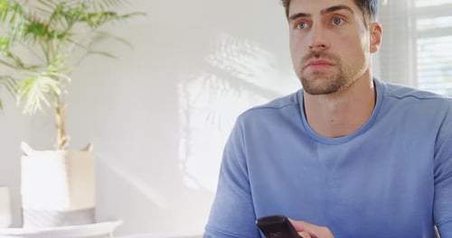 Man with Remote Sitting Indoors During Daytime
