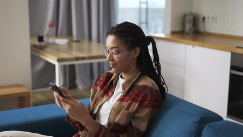 Woman Using Smartphone Sitting on Couch at Home