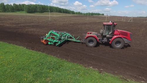 Agriculture Machine Tractor Plow and Spread Fertilizer on Cultivated Field Soil in Summer