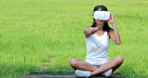 Woman watching with virtual reality device and sitting at the park