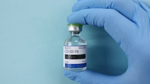 Gloved Hand Holding COVID-19 Vaccine Vial