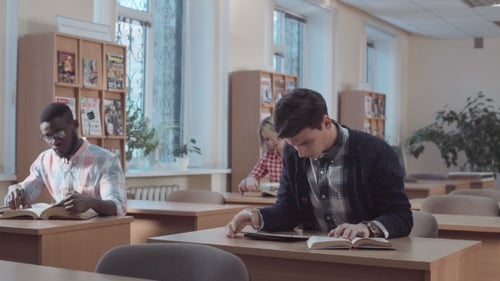 Man with Book and Tablet Looking in Library