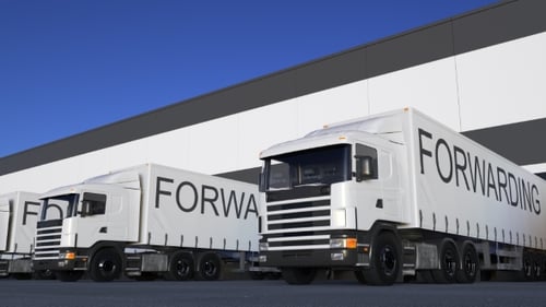 Freight Semi Truck with FORWARDING Caption on the Trailer Loading or Unloading