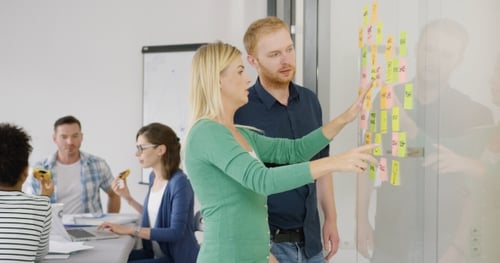 Team Discussing Project Using Sticky Notes in Office