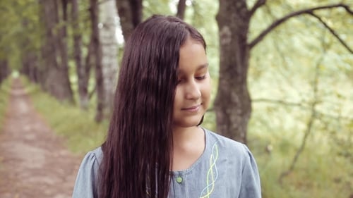 Girl Smelling Flowers on a Forest Path