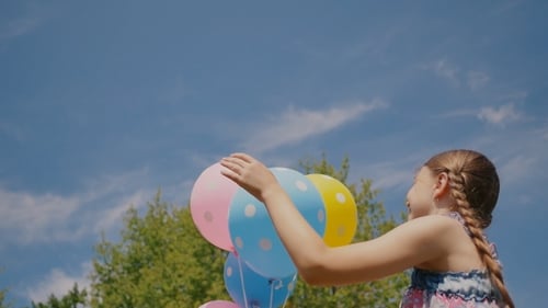 Happy Child Holding Colorful Polka Dot Balloons Outdoors