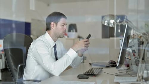 Ambitious Middle Aged Businessman Using His Cellphone in the Office