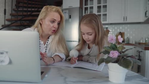 Mother Helping Daughter with Homework in Kitchen