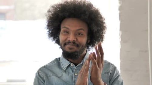 Man With Afro Smiling and Clapping Indoors