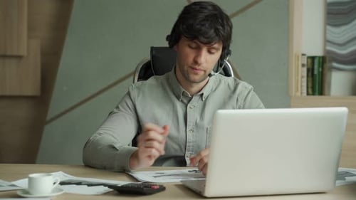 Man with Headset and Laptop Computer Having Video Conference at Office