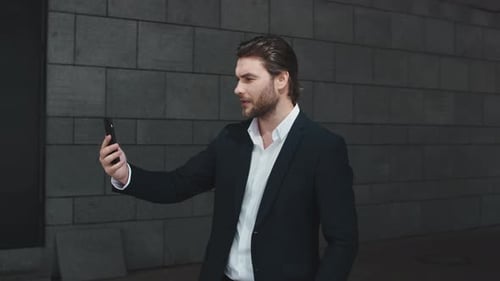 Serious Business Man Having Online Conference on Smartphone in Modern City