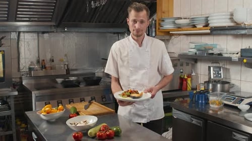 Chef Holding Plate of Fish in Commercial Kitchen