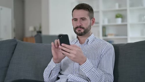 Adult Using Smartphone Device While Relaxing on Couch
