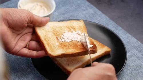 Hands Spreading Creamy Sauce on Toast with Knife