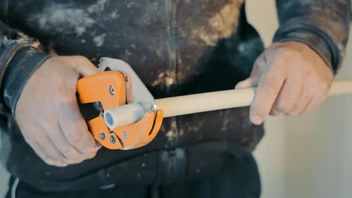 Man Cutting Plastic Pipe with Pipe Cutter