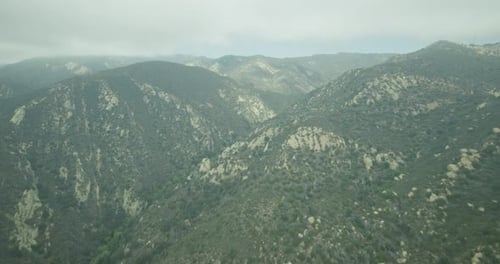 Fast tracking helicopter aerial shot over green hills, cloudy day