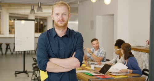 Confident Man Smiling in Modern Office with Team
