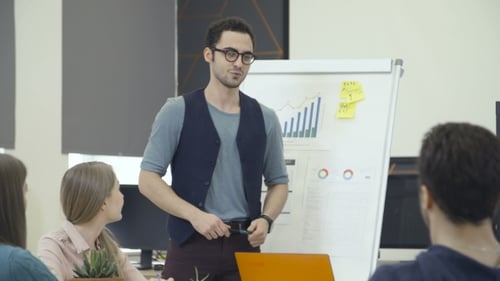 Young Adult Man Presents Data to Colleagues