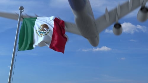 Avión comercial aterriza detrás ondeando la bandera mexicana