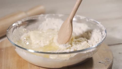 Mixing Dough with Wooden Spoon in Kitchen