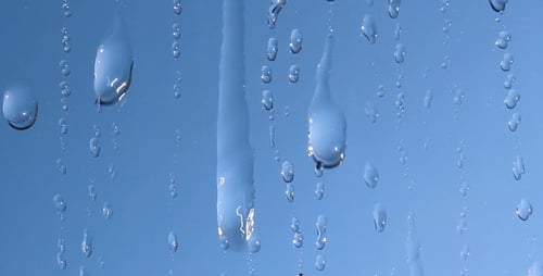 Water Droplets Sliding Down Glass on Blue Background
