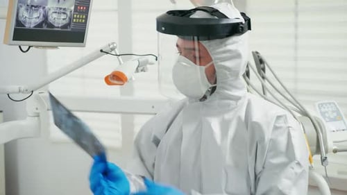 Dentist Studies X-Ray in Personal Protective Equipment