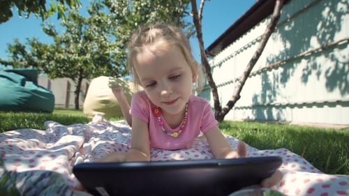 Charming Girl Posing with Tablet on Lawn