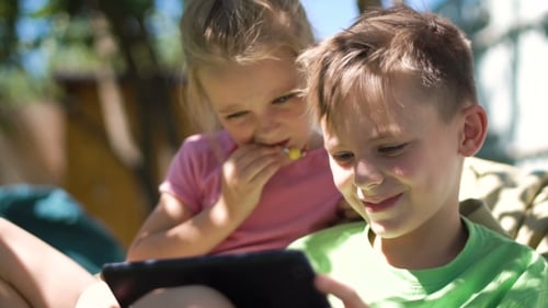 Children Smiling Using Tablet Outdoors on Sunny Day