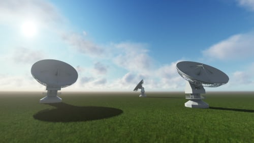 Rotating Satellite Dishes in Green Field Under Blue Sky
