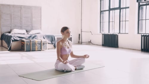 Woman Meditating on Yoga Mat in Bright Apartment