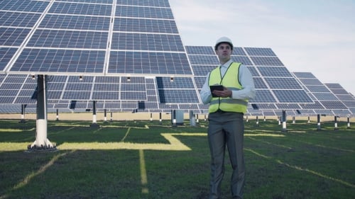 Solar Panel Technician Using Tablet Near Array