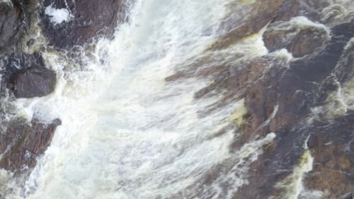 Rising Aerial Shot Looking Down at Raging Waterfall in a River