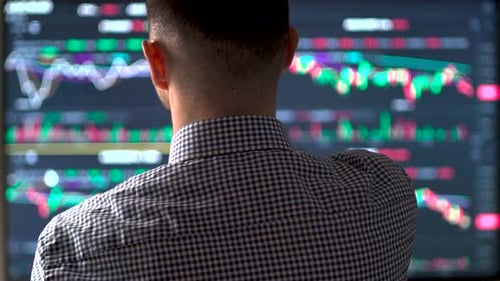 Man Analyzing Stock Market Charts on Computer Screen